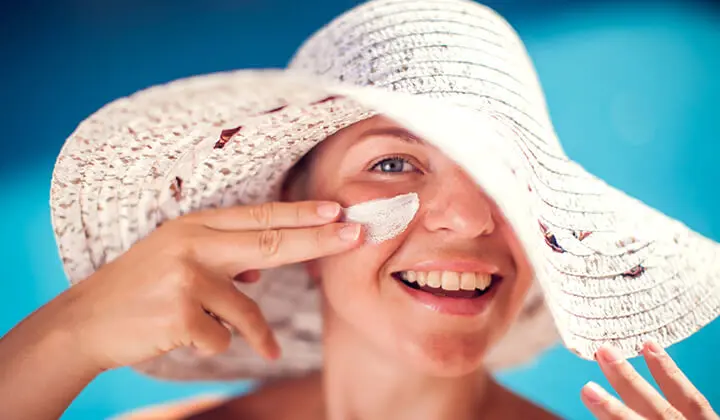 Frau trägt Sonnencreme im Gesicht auf